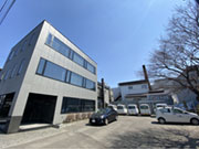 【本社屋敷地内風景】
興和ビルの本社屋駐車場には整備された作業車両が 並び、部材を積込み日々現場に向かいます。 無料駐車 スペースも完備しているので車通勤が可能です。 本社屋の横に見えるのが研修棟兼倉庫です。