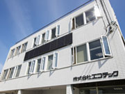 【外観】1Fは設備などの資材を置く、倉庫となっています。屋上は、まわりに高い建物もないことから見晴らしがよく、気分転換には最高です。道路を挟んだ、反対側に社員用の駐車場を確保しています。
